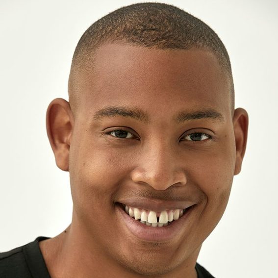 Shaun - ACC Trainer Smiling man with short hair wearing a black top against a neutral background.