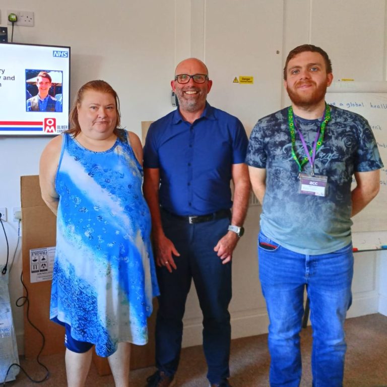3 people stood in front of monitor.
