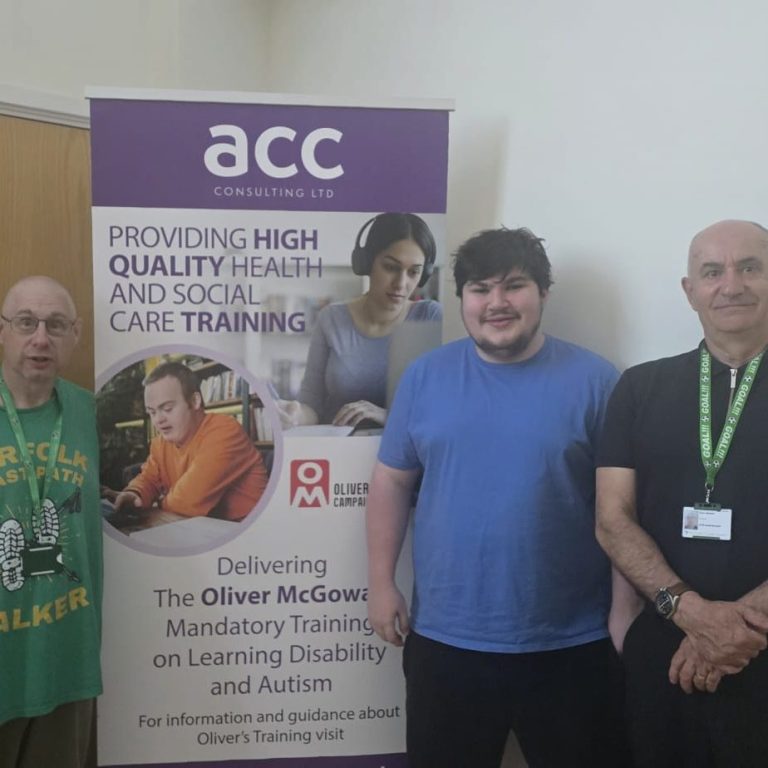 3 people stood in front of exhibition banner.
