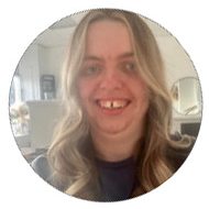 Smiling person with long, wavy hair in a bright indoor setting.